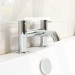 A chrome-plated bath filler with a sleek, modern design, mounted on a white marble bathroom wall.