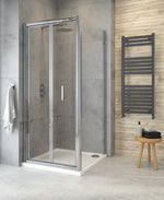 A bifold shower door installation in a bathroom with chrome handles and a semi-frameless design, featuring clear glass panels and a shower tray.